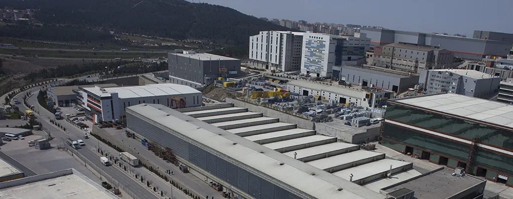 Organize sanayi bölgesinde fabrika çatıları ve yollar, havadan geniş görünüm