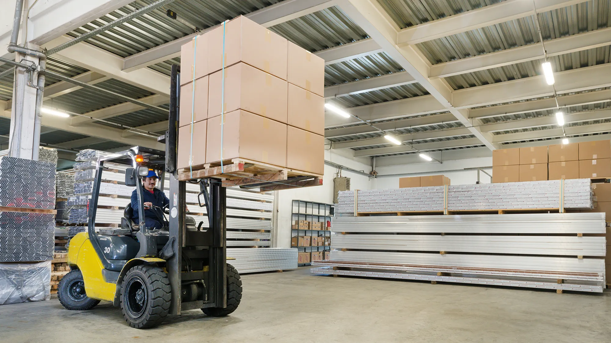 Depoda forkliftin kaldırdığı koli paleti ve sevkiyata hazır alüminyum profil yığınları